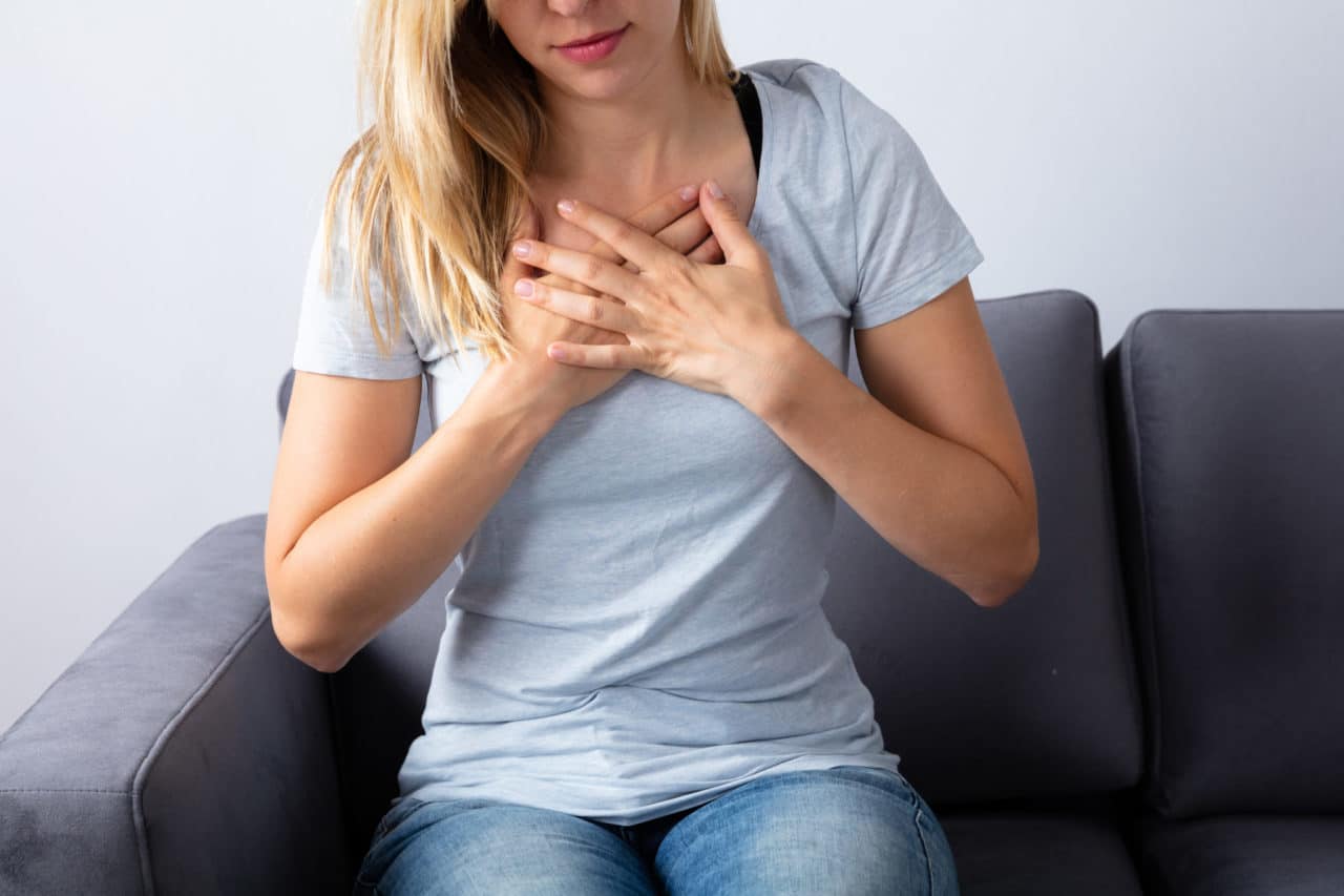 A person sitting on a couch and crossing their hands over their chest