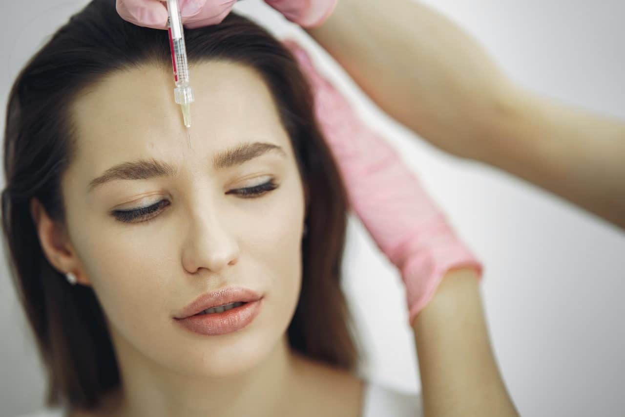 Woman getting a liquid facelift serum injected into her middle brow