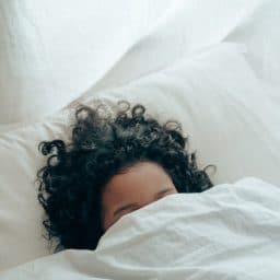 person sleeping with their head under the covers