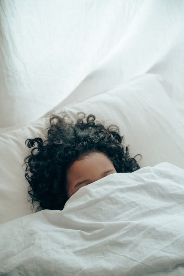 person sleeping with their head under the covers