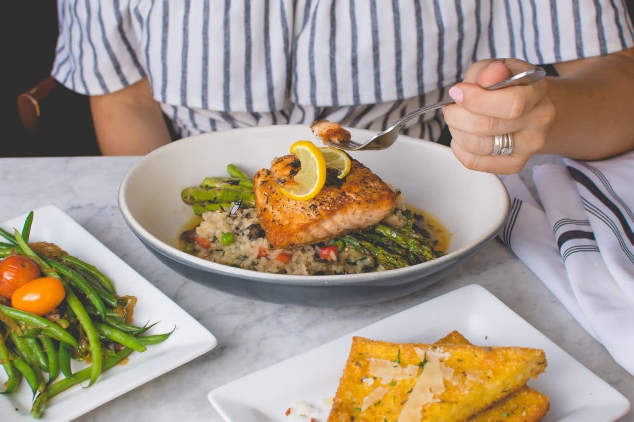 Someone sitting at a table with a fish dinner.