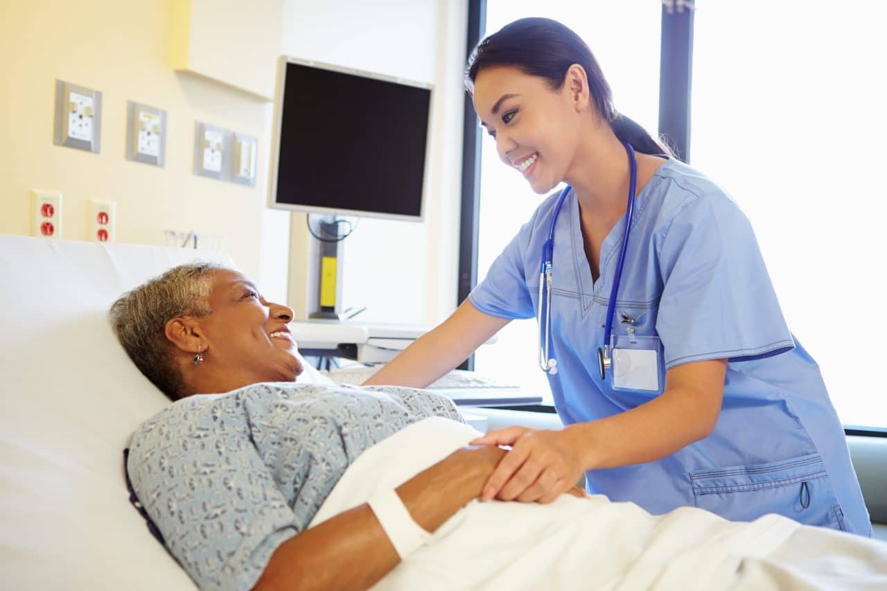 Nurse checking in on older female patient after surgery.