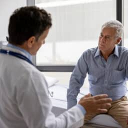 Doctor talking to a patient in a consultaton at his office practice - healthcare and medicine concepts