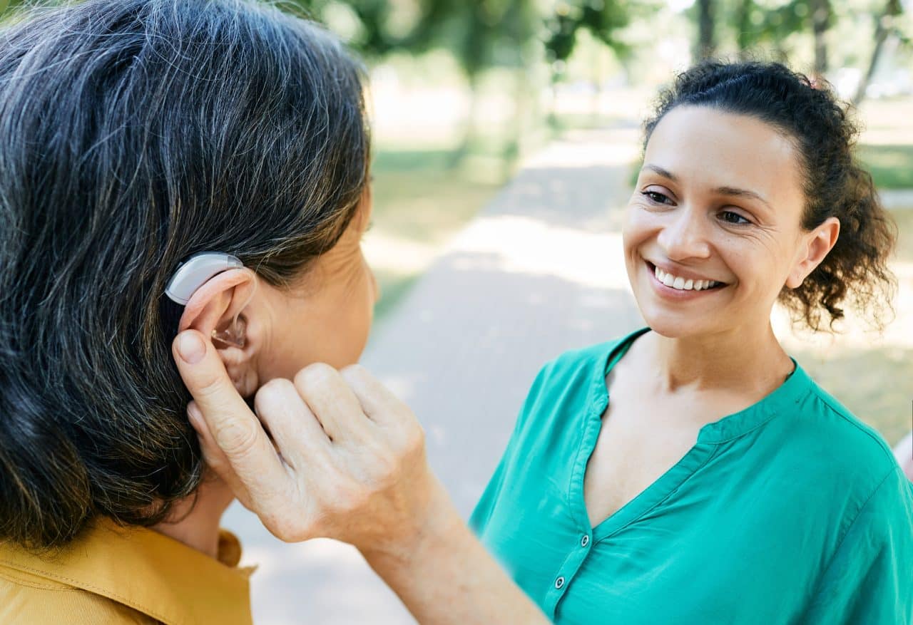 Woman with a hearing aid talking to her friend in the park.