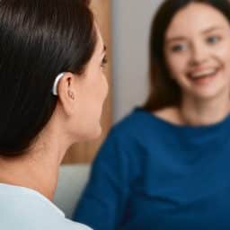 Young woman with a hearing aid talking with her friend.