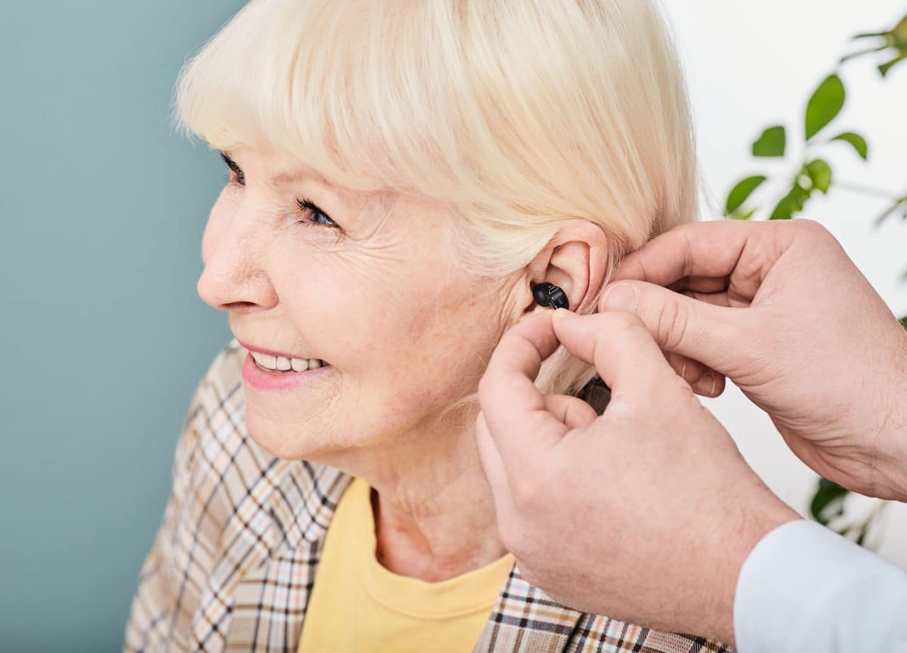 Smiling senior woman getting fitted for a hearing aid.