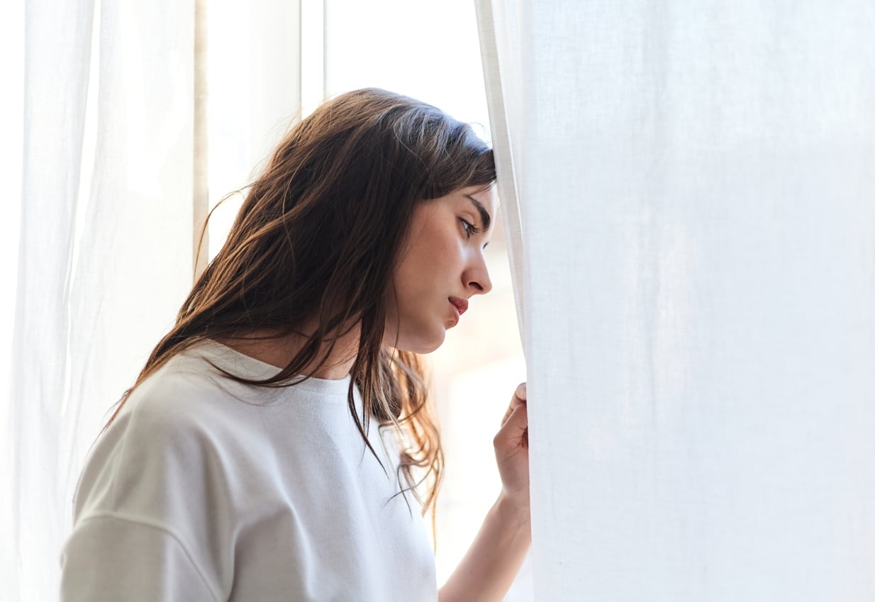 Woman with depression looking out the window.