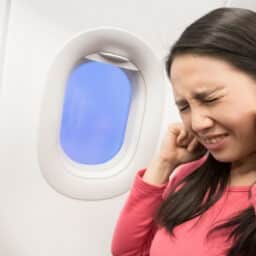 Young girl holding her ears on a plane