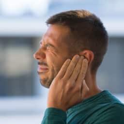 Man with tinnitus holds ear