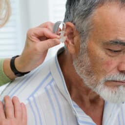 Audiologist positioning a man's hearing aid