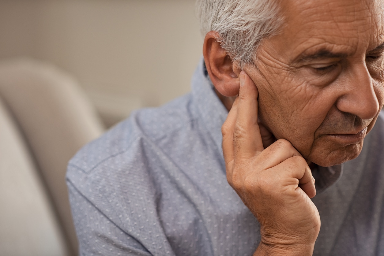 Man with hearing loss holds ear