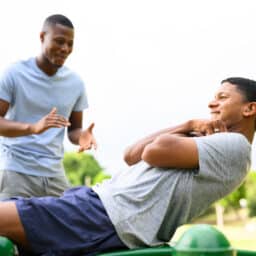 Young man wearing hearing aid doing sit ups on sports equipment in park