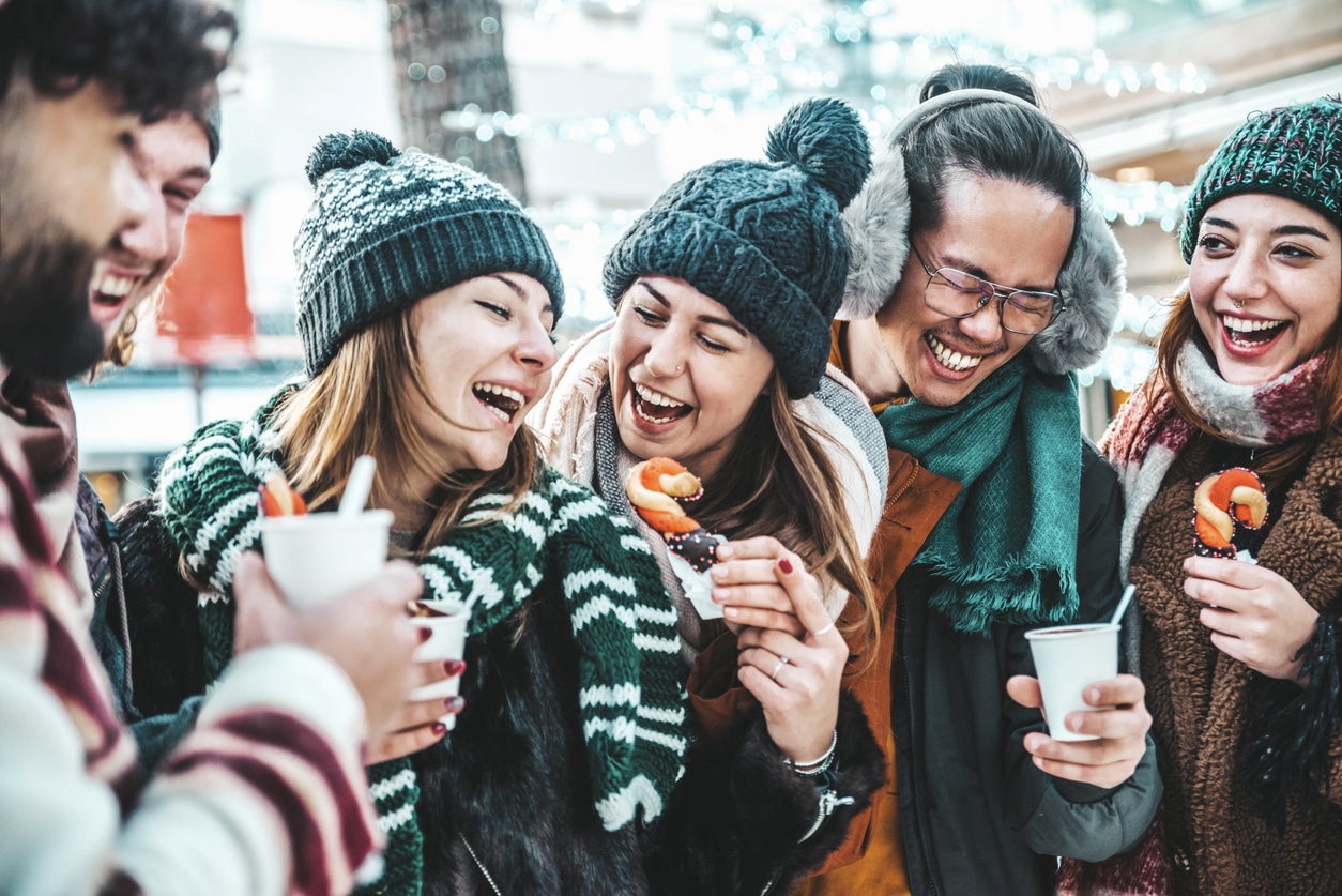 Laughing friends drinking hot chocolate at the Christmas market.