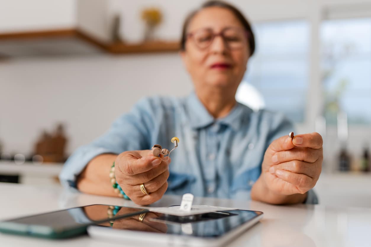 Senior woman holding her hearing aids.