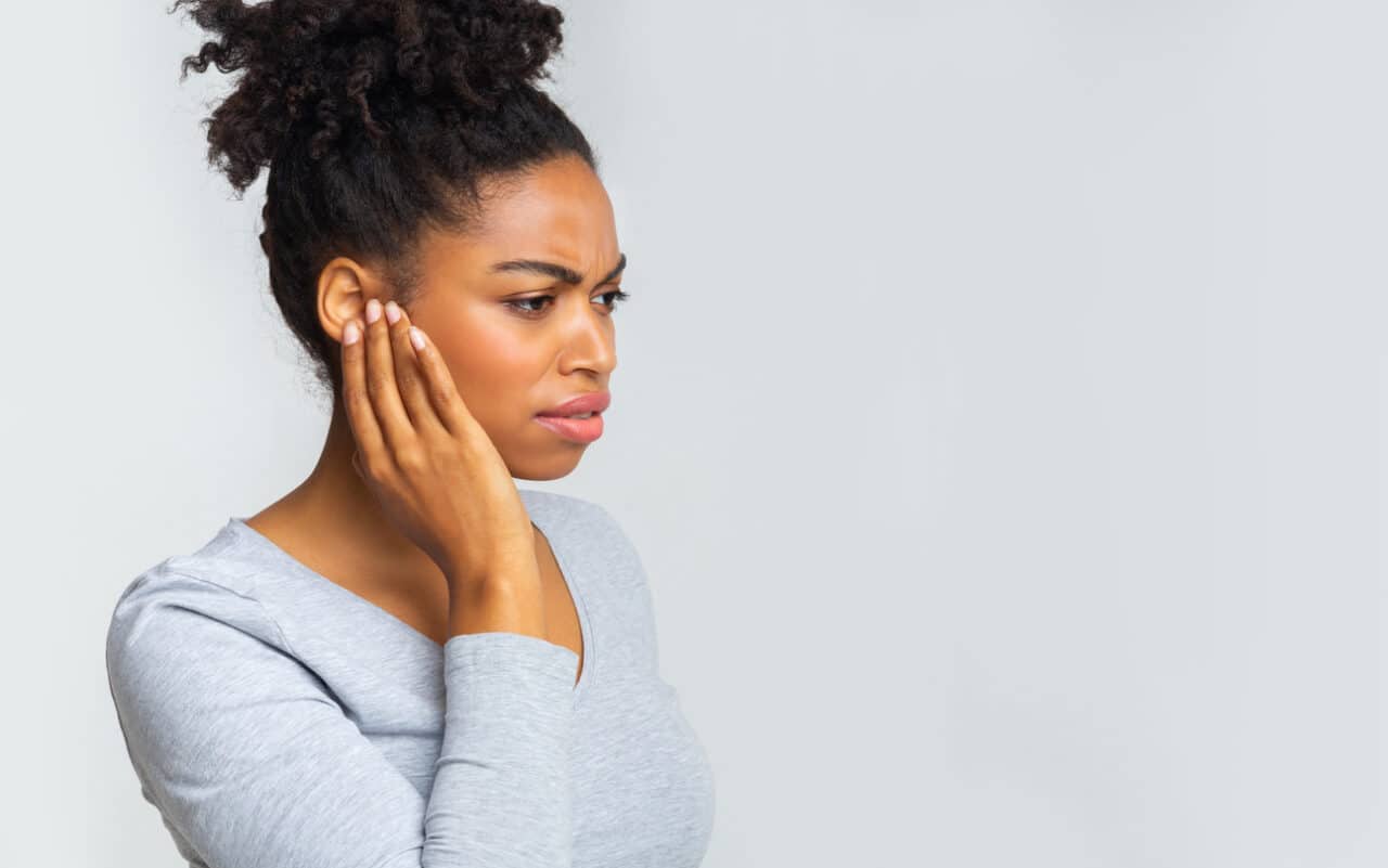 Woman with an ear infection holding her affected ear.