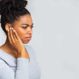 Woman with an ear infection holding her affected ear