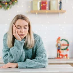 Young woman looking stressed at a table with holiday decorations behind her