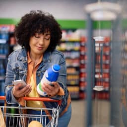 Woman at the grocery store looking at a milk bottle